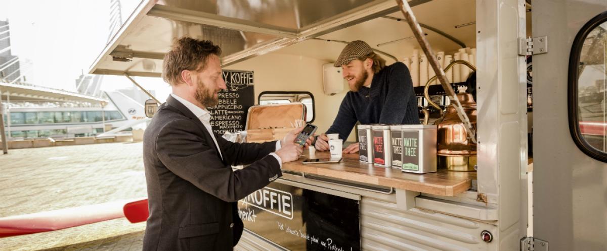 Foto van een klant die bij een foodtruck een bestelling afrekent bij een mobiele pinautomaat