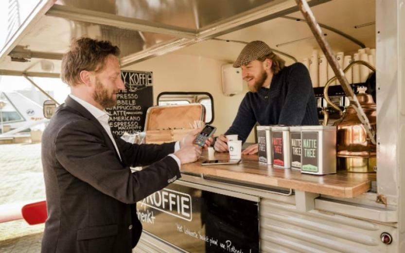 Foto van een klant die bij een foodtruck een bestelling afrekent bij een mobiele pinautomaat