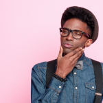 porttretfoto van een nadenkende jongeman met een bril op en bretels over zijn schouders 